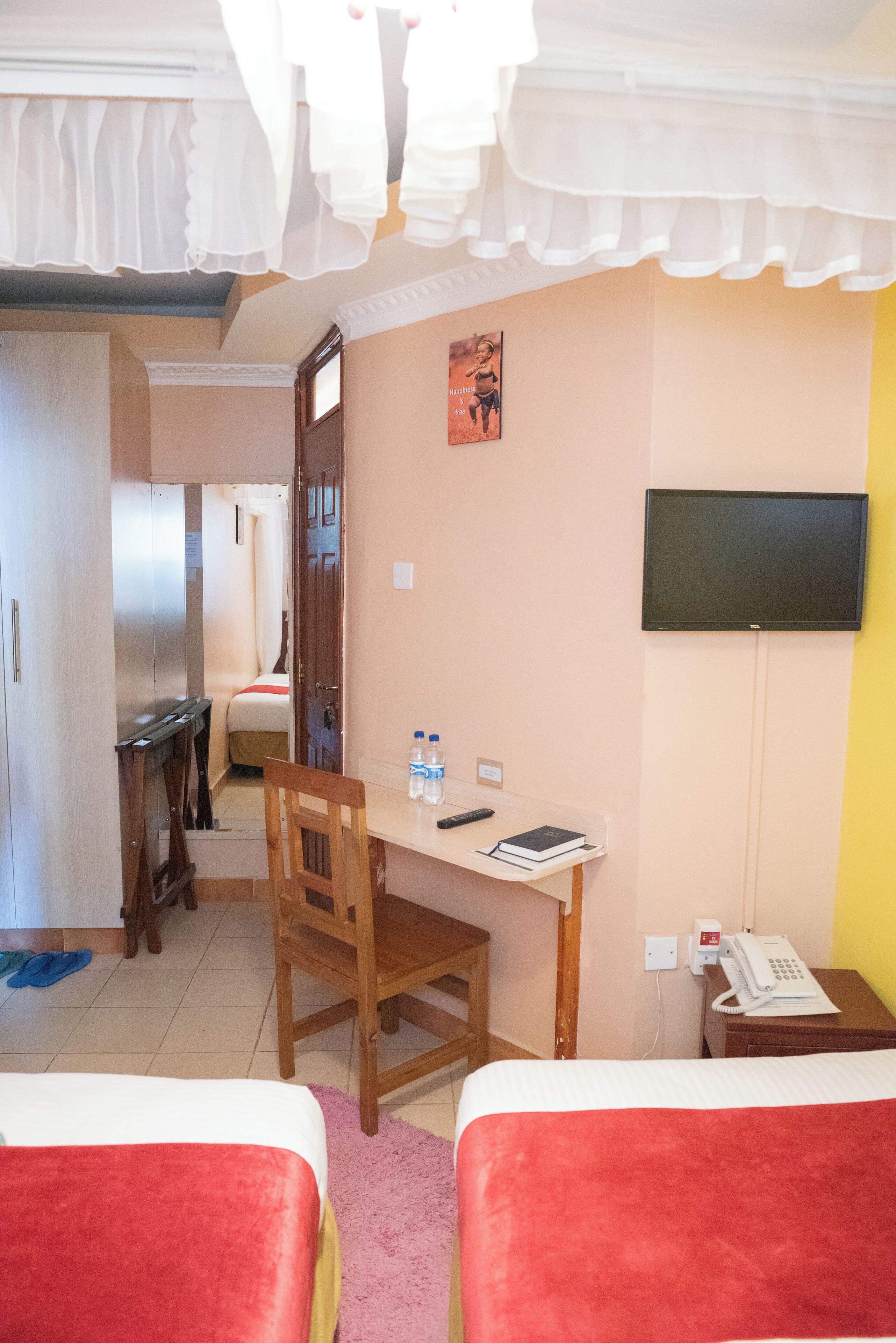 A hotel room with two beds, a desk with a chair, a TV, and a telephone.