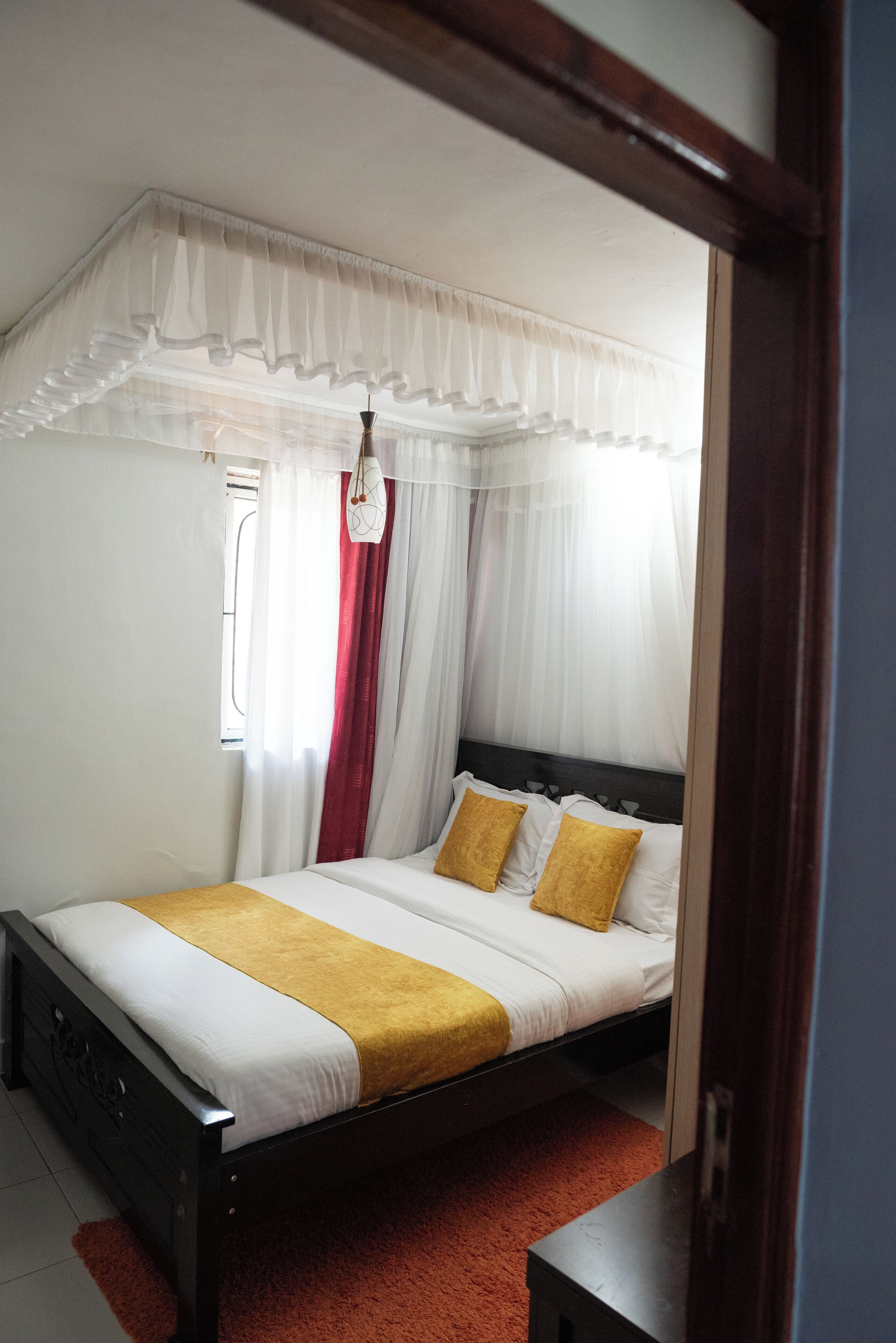 A bed with a canopy, white bedding, and two gold pillows.
