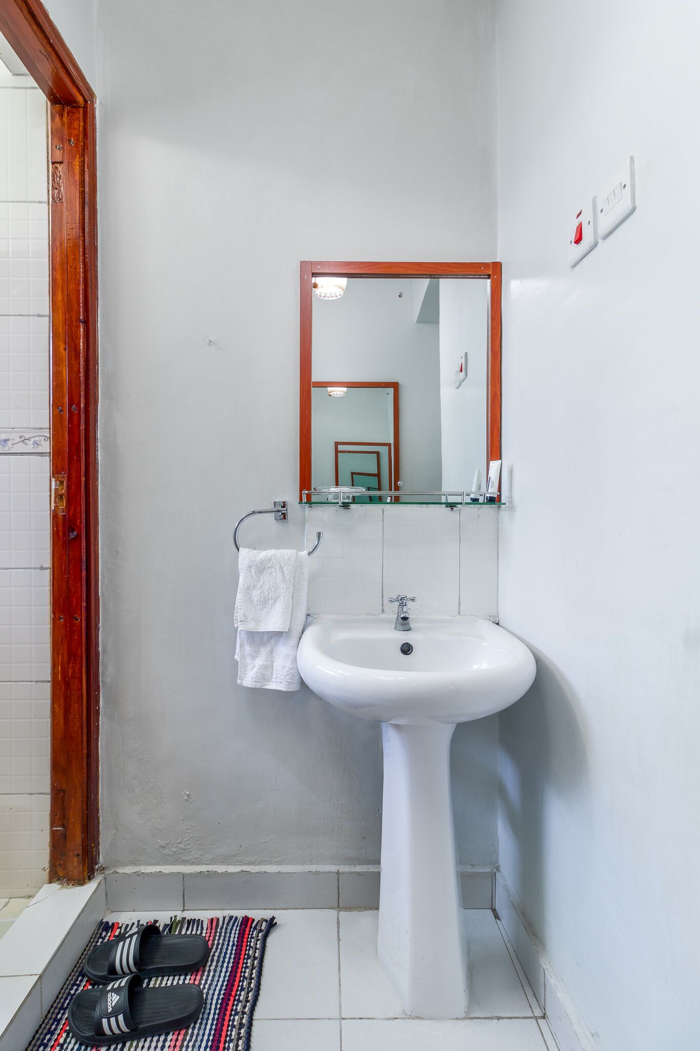 A bathroom with a white sink, a mirror, and a towel rack.