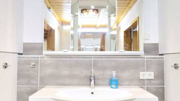 A bathroom with a white sink, a mirror, and a wooden ceiling.