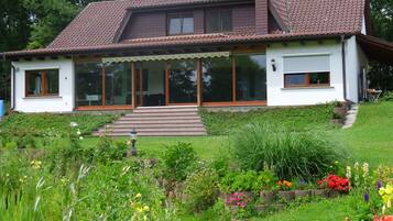 A two-story house with a sloped roof, large windows, and a front porch.