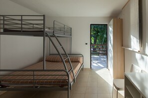 A bunk bed room with a desk and chair, a window with a view of greenery, and a door leading outside. - Camping&Residence Il Pioppeto (Vasto)