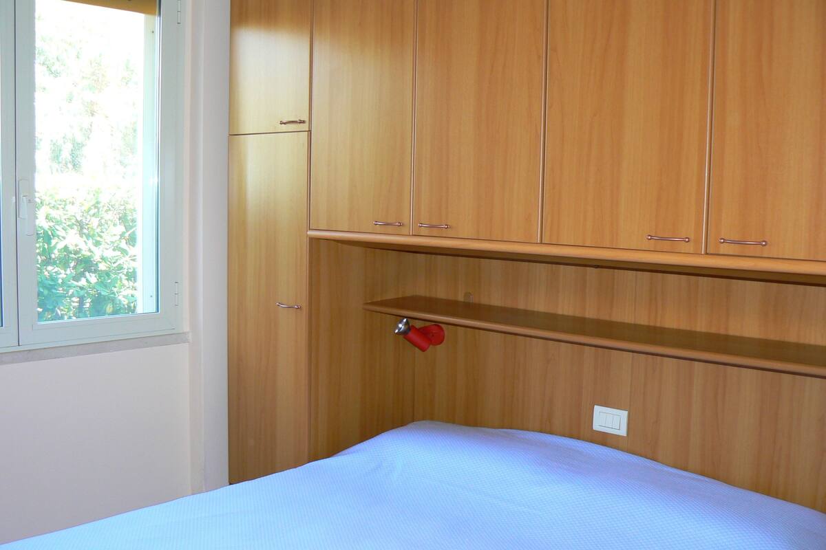 A bedroom with wooden cabinets, a bed, and a window.