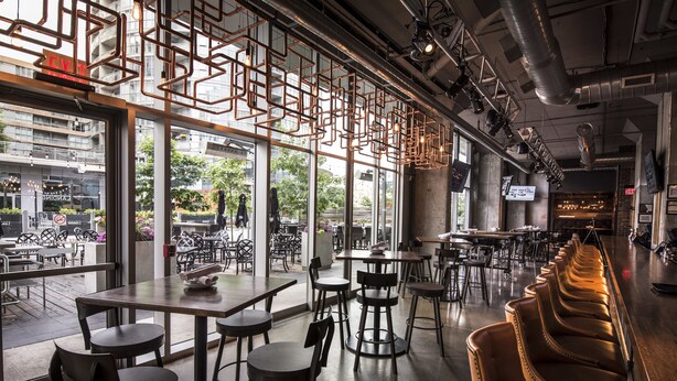 An interior with tables and chairs, a bar area, and large windows offering a view of the street. - A&A Suites in the heart of Downtown Toronto (Toronto)