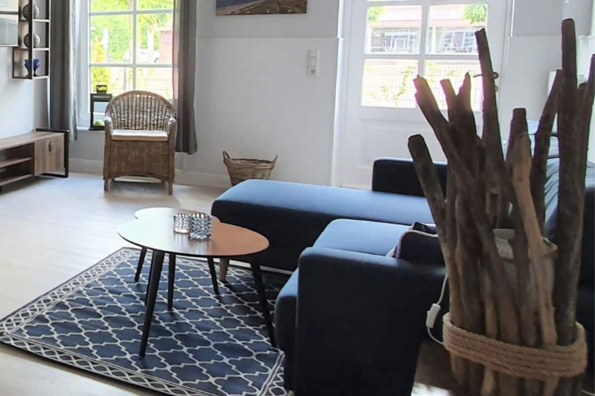A living room with a blue sofa, a round coffee table, a wicker chair, and a rug.