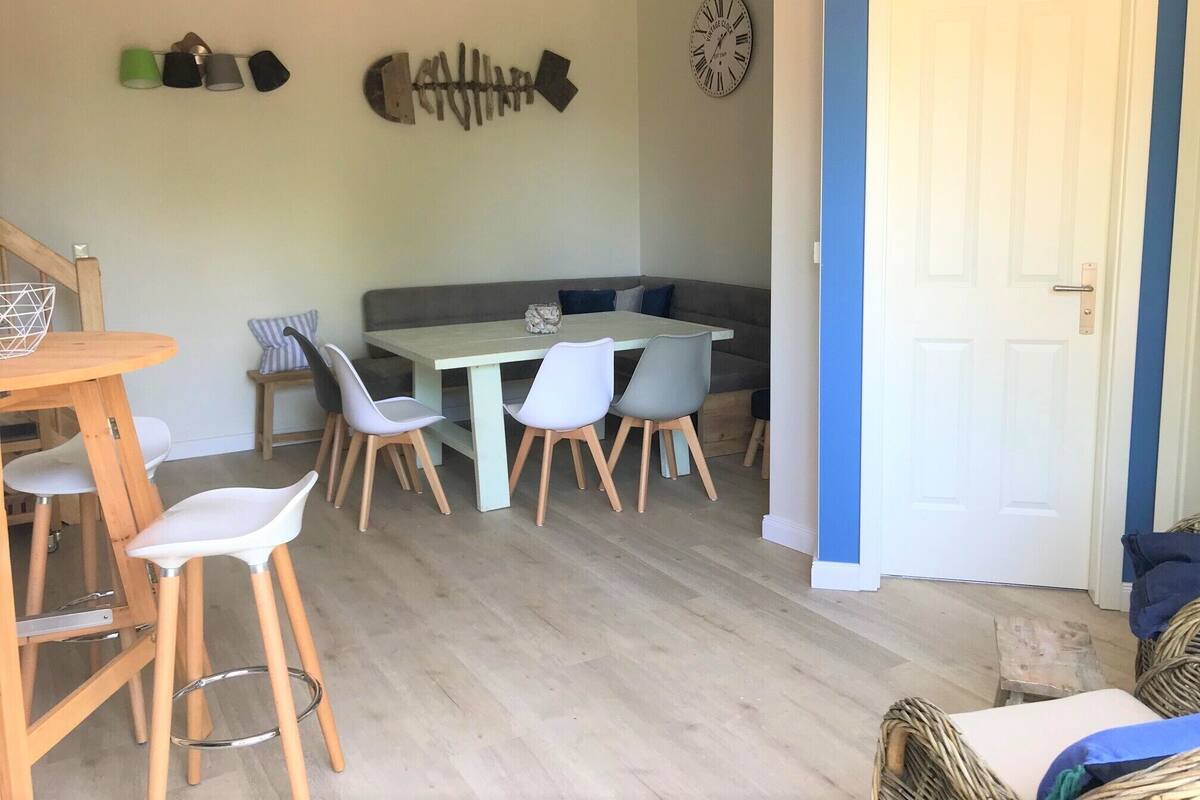 A dining area with a table and chairs, a wall clock, and a door.
