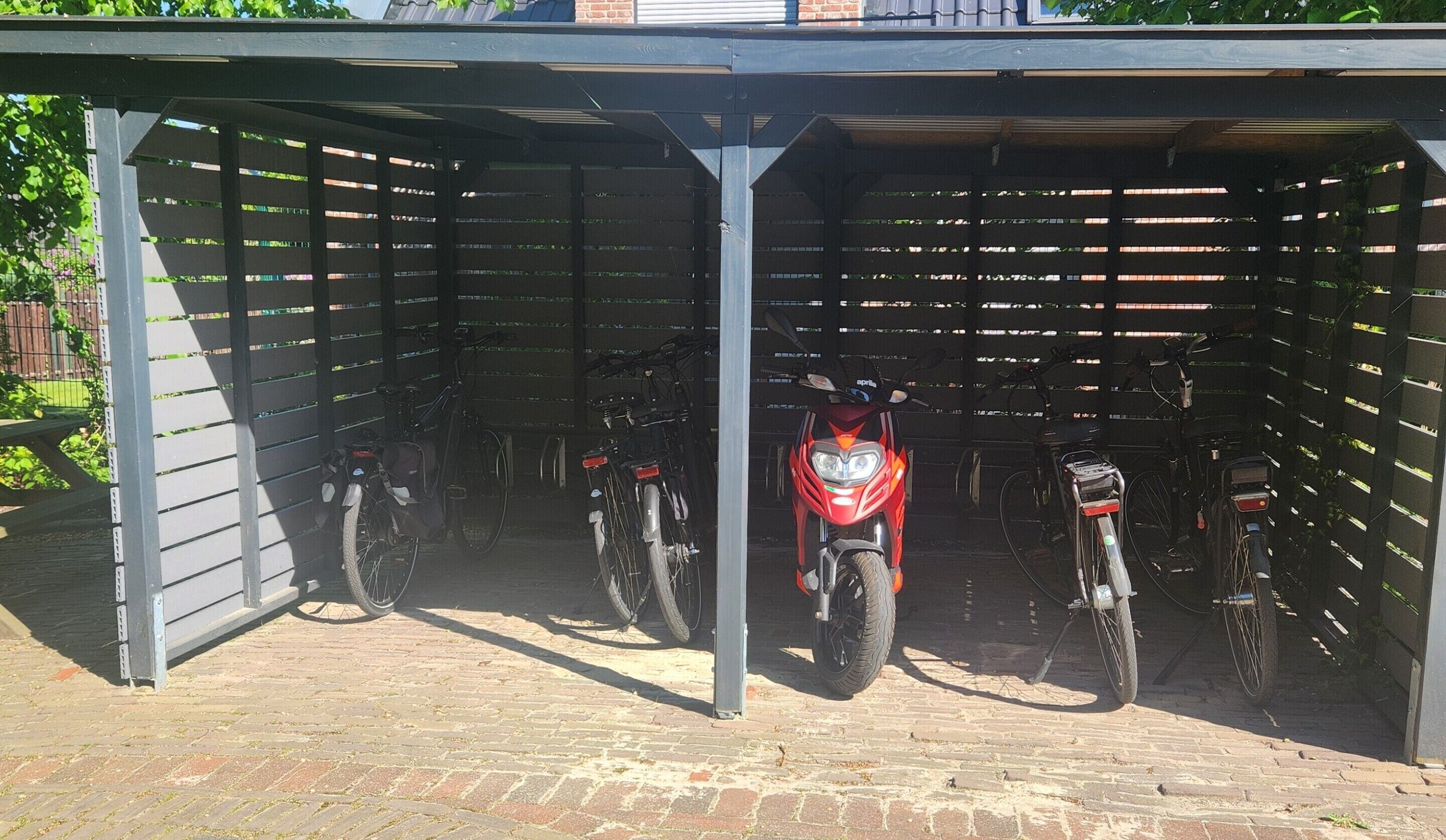 Un área de estacionamiento techada con varias bicicletas y una motocicleta roja.