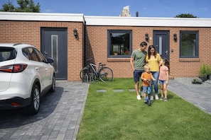 A family in a modern house with a car and bicycles in the driveway. - Hotel Friesischer Hof (Hage)