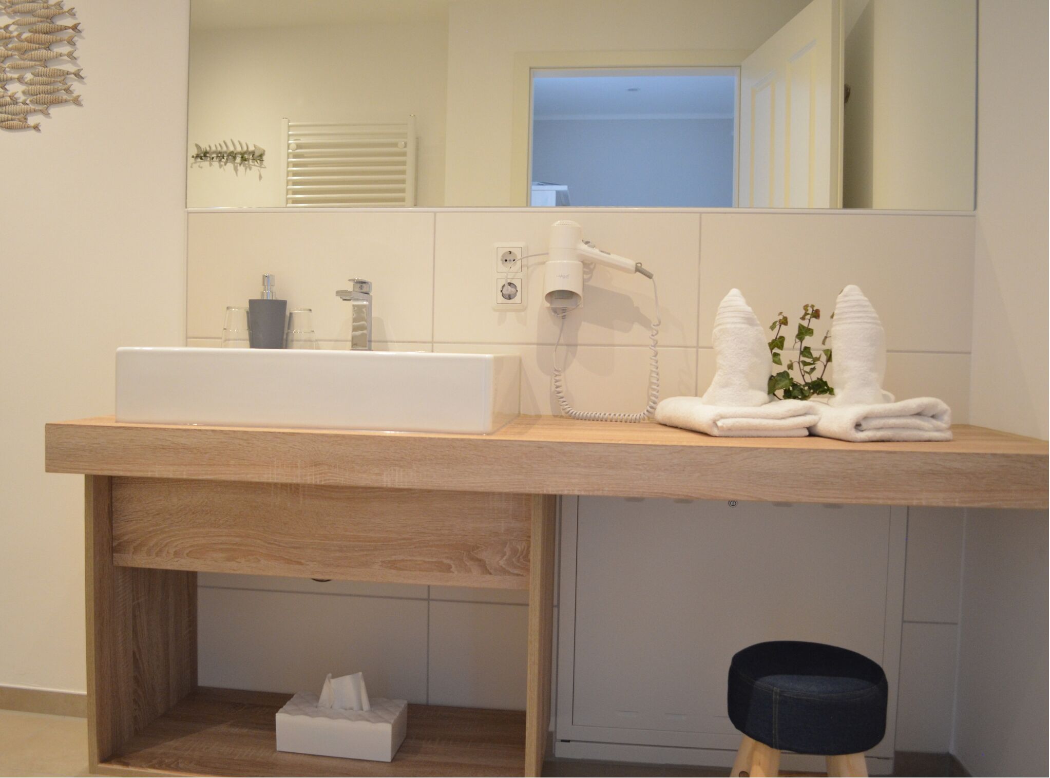 Een moderne badkamer met een grote wastafel, een haardroger en handdoeken op het aanrecht.