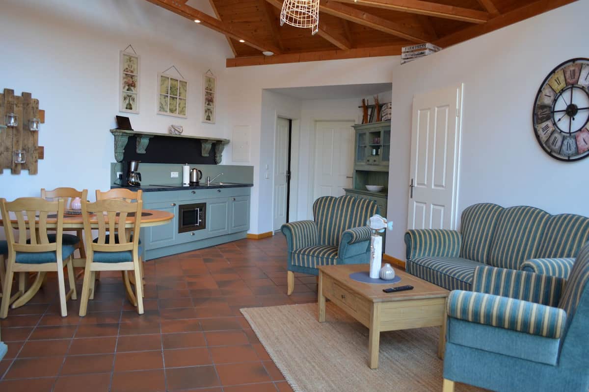 A spacious living area with a dining set, sofas, and a kitchen in the background.