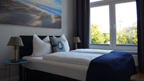 A hotel room with a large bed, two bedside lamps, a painting on the wall, and a view of the city through the window. - Hotel Friesischer Hof (Hage)