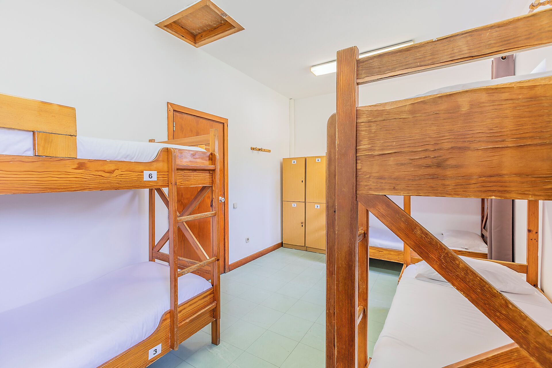 A dormitory room with bunk beds, wooden lockers, and a small window.