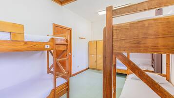 A dormitory room with bunk beds, wooden lockers, and a small window.