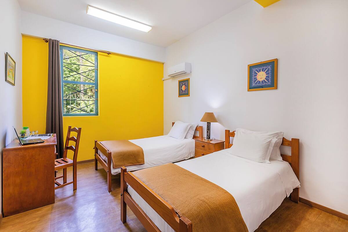 Une chambre d’hôtel avec deux lits, un bureau, une chaise et une fenêtre donnant sur un paysage agréable.