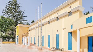 A building with multiple blue doors, a yellow facade, and a clear sky. - HI Faro- Pousada de Juventude - Hostel (Faro)
