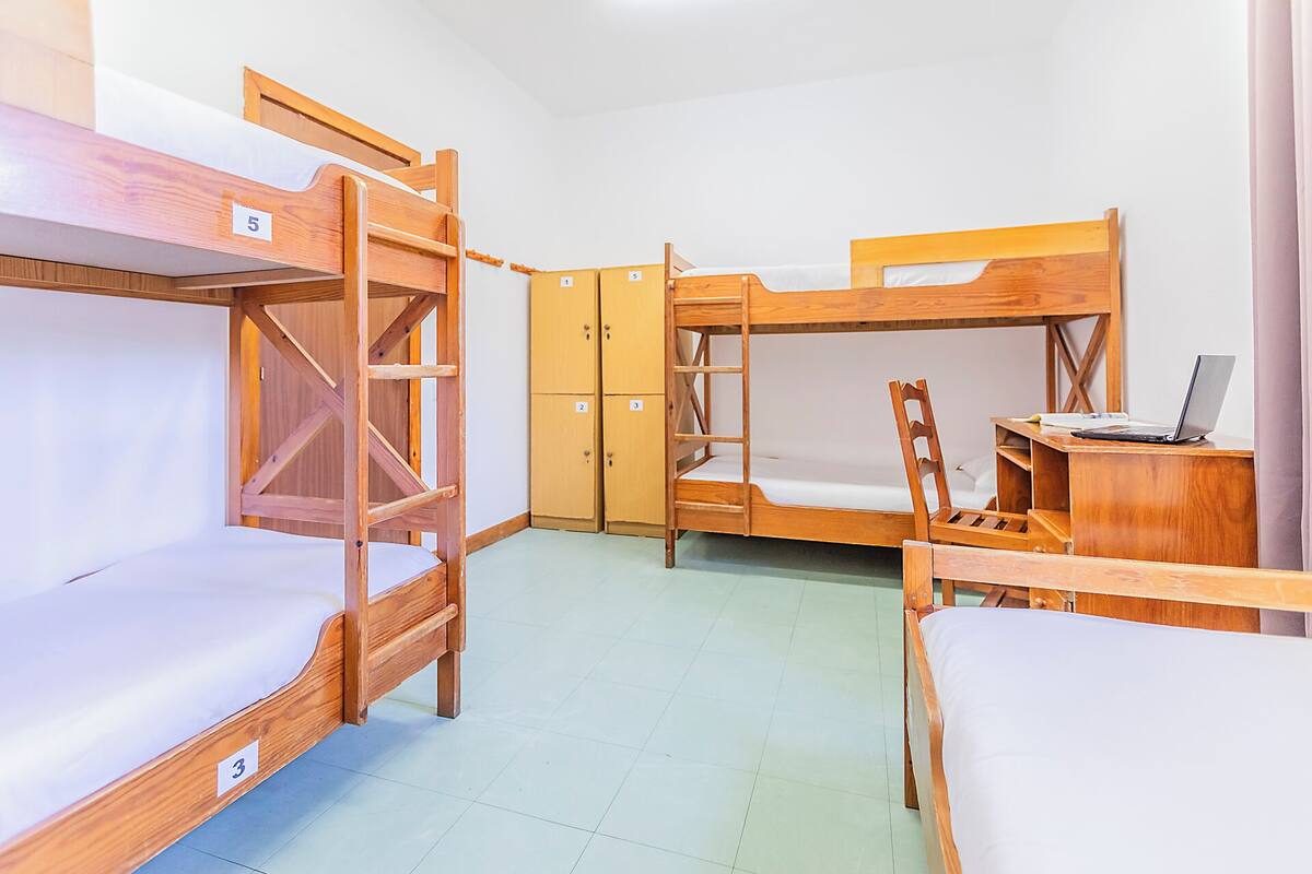 Une chambre de dortoir avec des lits superposés, un bureau et une chaise.