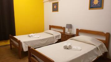 Two single beds with wooden frames, white bedding, and a small bedside table with a lamp.