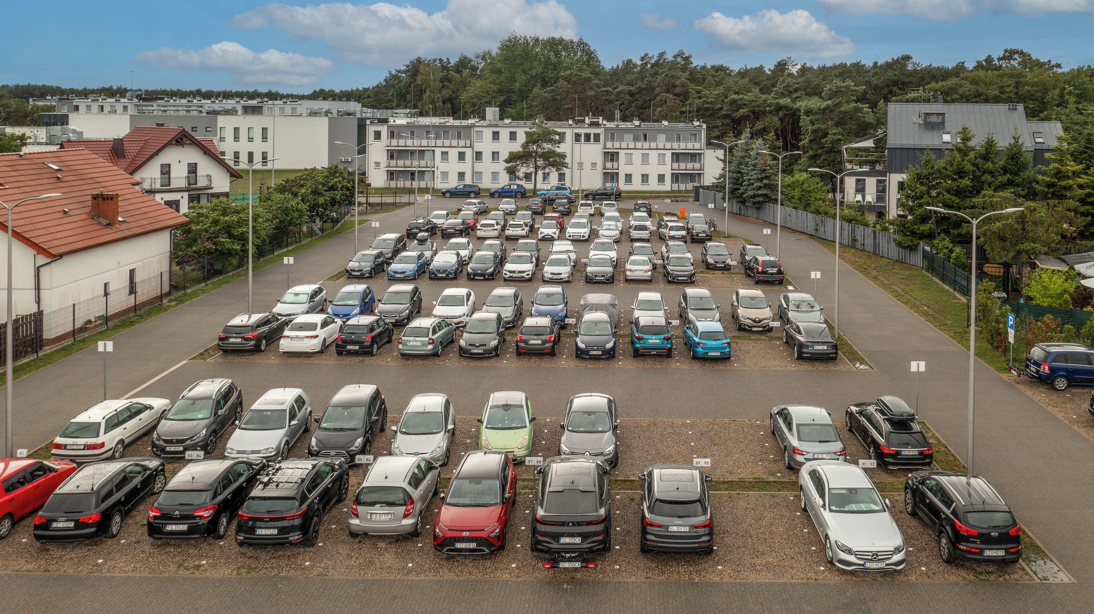 A parking lot with multiple rows of parked cars.