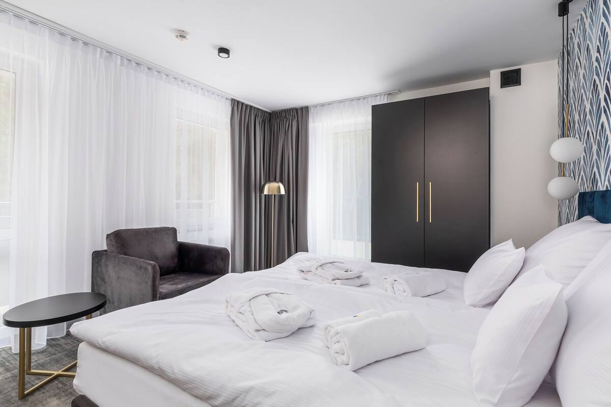 A hotel room with a bed, a chair, a desk, and a wardrobe.