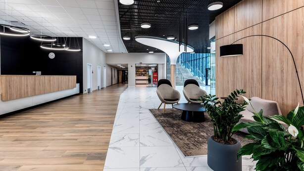 Un hall d’entrée moderne comprenant un comptoir d’accueil, un espace salon et un escalier menant aux étages supérieurs.