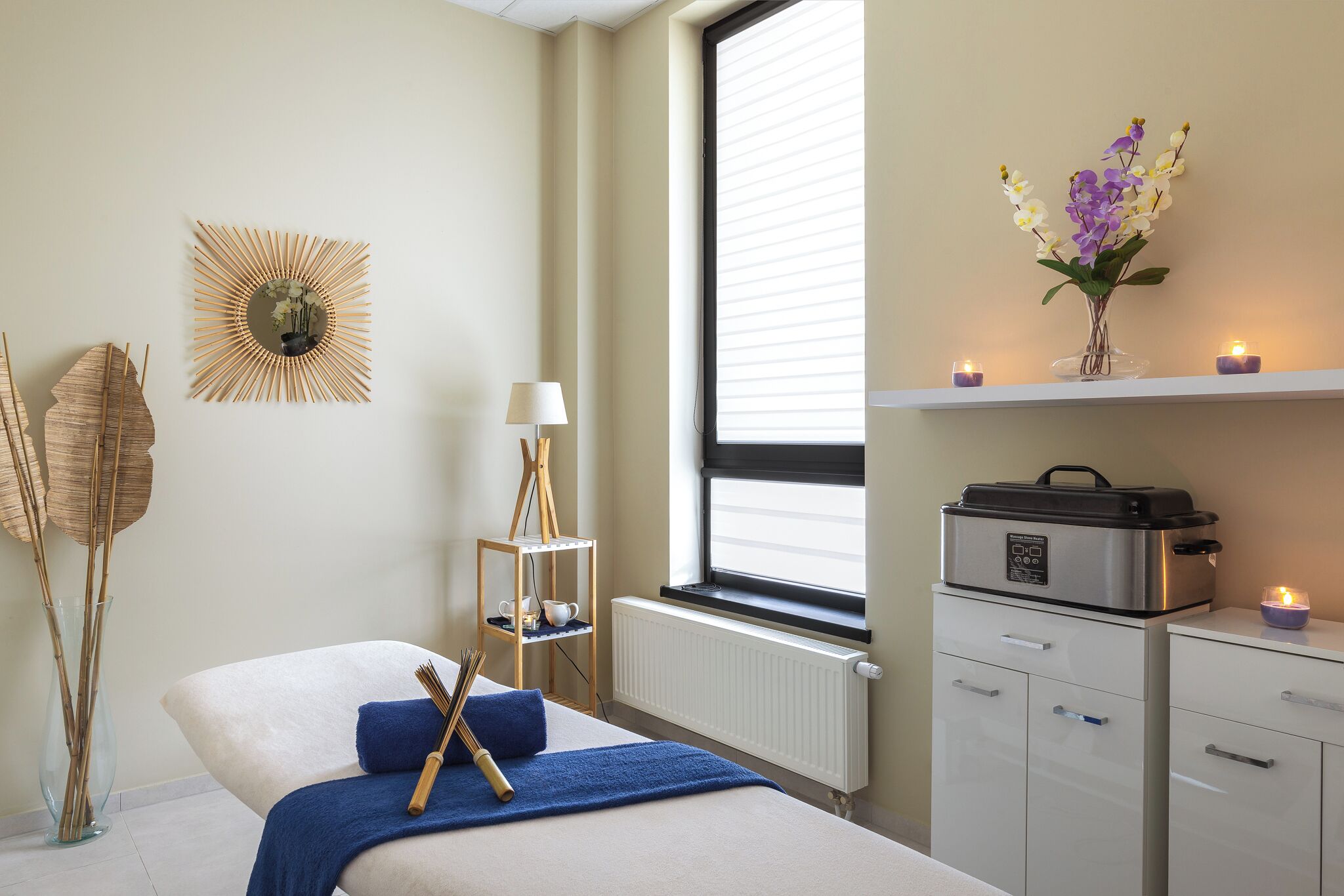 A bedroom with a bed, bedside table, lamp, and a window with blinds.