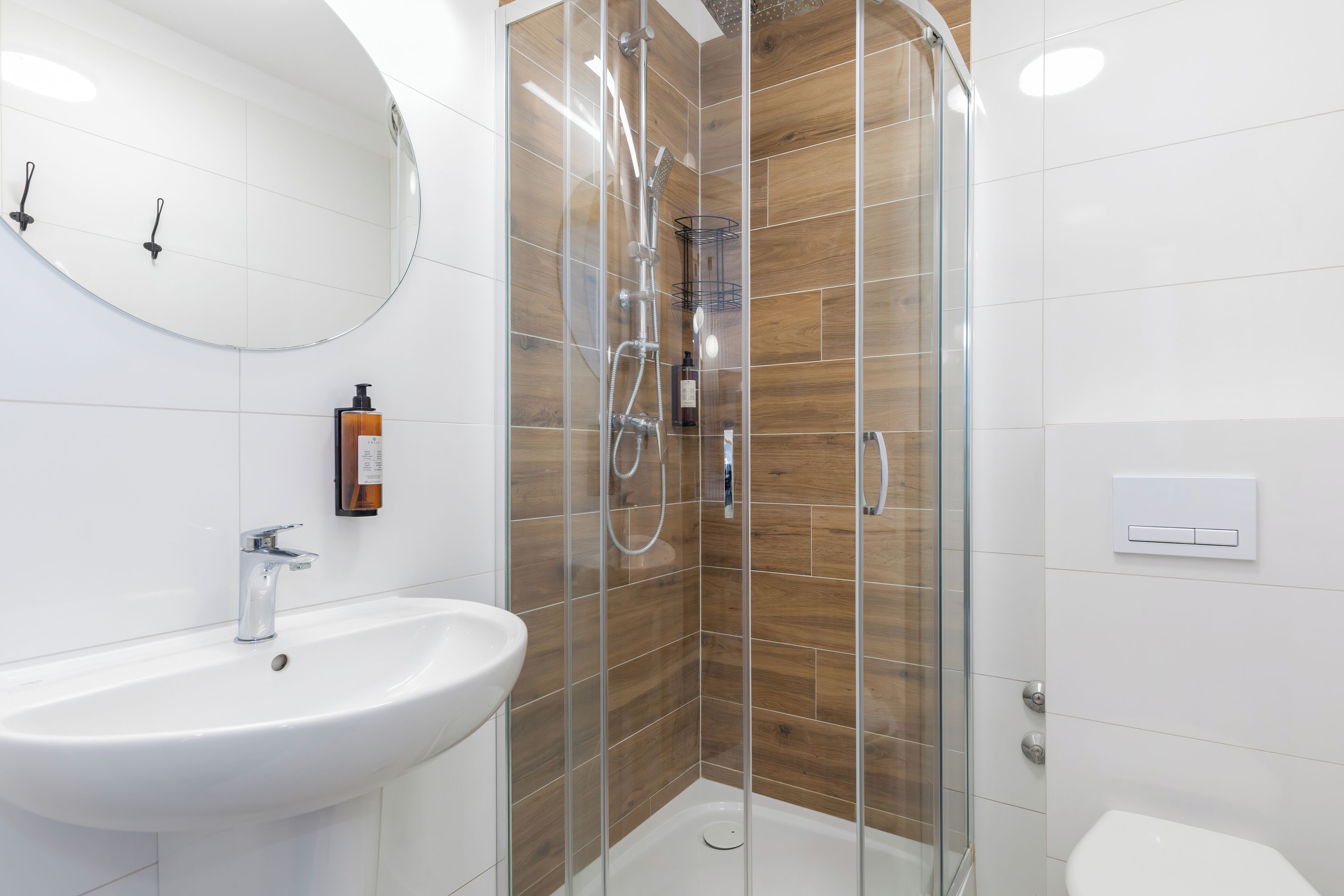 A modern bathroom with a glass-enclosed shower, a white sink, and a mirror.