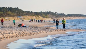 Une plage où l’on voit des gens se promener et d’autres assis sur le sable.