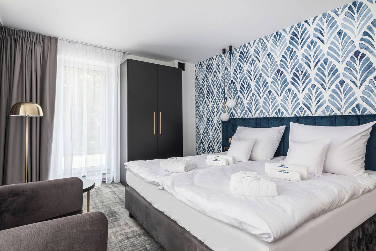 A hotel room with a large bed, a desk, and a chair.