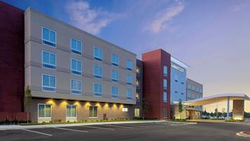 A multi-story hotel with a modern design, featuring a parking lot in front.