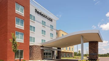 Un hotel Fairfield Inn & Suites by Marriott con diseño moderno, que cuenta con una entrada cubierta y un área ajardinada con plantas.