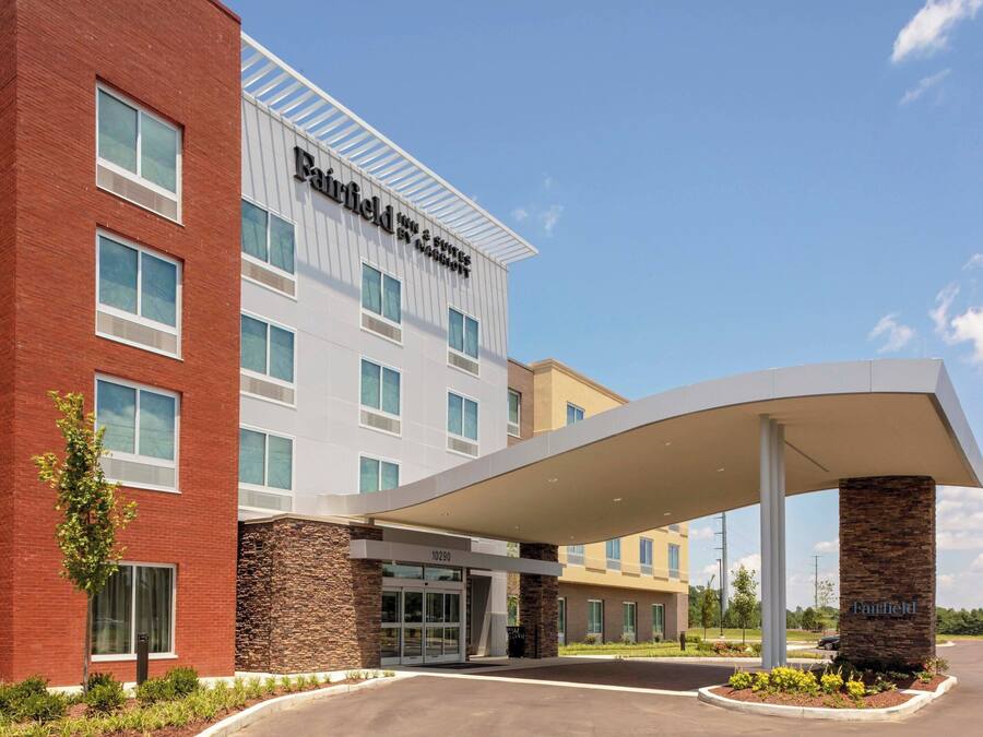 Un hotel Fairfield Inn & Suites by Marriott con diseño moderno, que cuenta con una entrada cubierta y un área ajardinada con plantas.