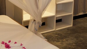 Un dormitorio con cama a dosel, una mesita de noche blanca y un armario de madera.