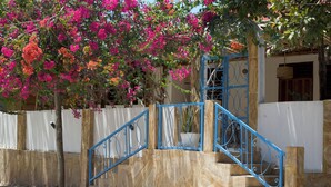 Una escalera con barandillas azules que lleva a una puerta blanca, rodeada por una pared color crema y una valla blanca.
