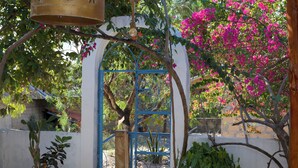Un jardín con una verja azul, plantas en macetas y un colgador con luz.
