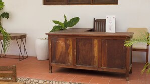 Un mostrador de recepción de madera con un letrero, una planta en maceta y una silla.