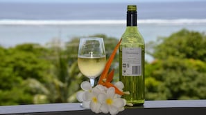 Une bouteille de vin Chardonnay et un verre de vin blanc sur un balcon avec vue sur l’océan.