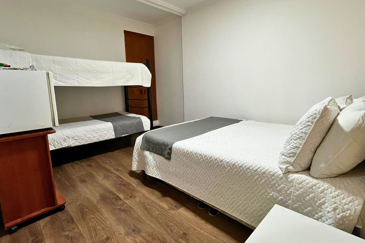 Een studentenkamer met stapelbedden, een bureau en een kledingkast.