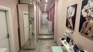 A corridor with a reception desk, a mirror, and artwork on the walls. - F Rooms (Naples)