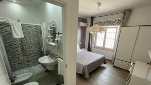 A modern bathroom with a shower, toilet, and sink. - F Rooms (Naples)
