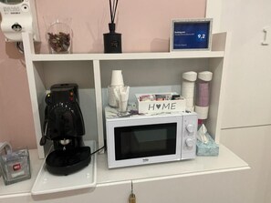 A kitchenette with a coffee maker, microwave, and a sign that says 'HOME'. - F Rooms (Naples)