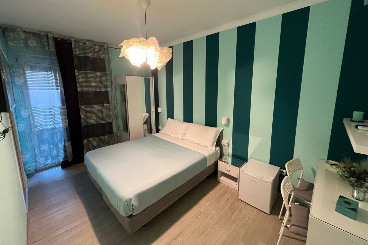 A bedroom with a bed, bedside table, and a desk with a chair.