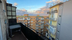A balcony with a view of multi-story residential buildings, a metal railing, and a small table. - F Rooms (Naples)