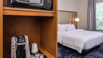 A hotel room with a bed, a minibar, a microwave, and a coffee maker.