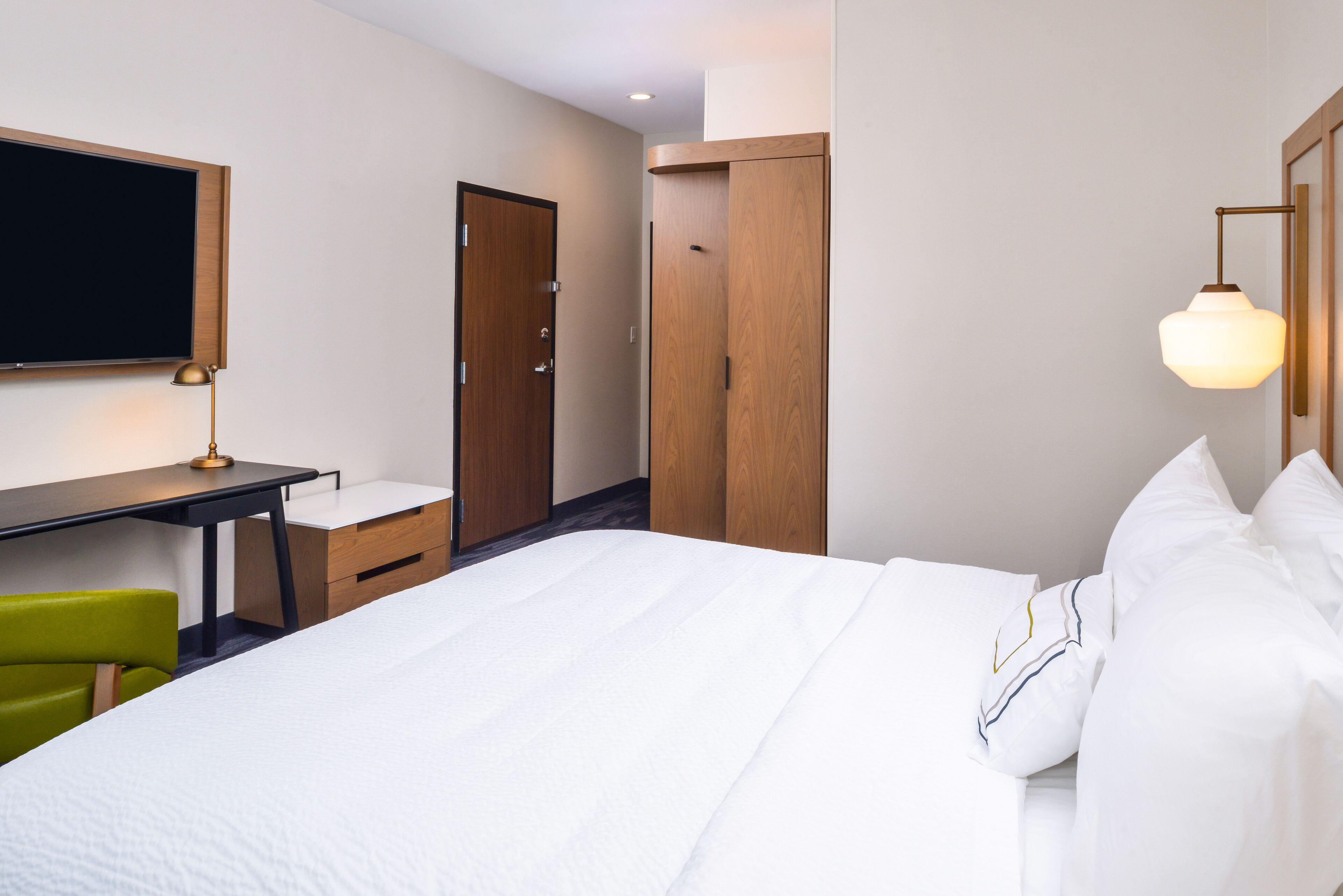 Una habitación de hotel con una cama, un escritorio, una silla y un armario.