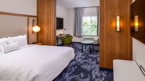 Habitación de hotel con una cama grande, un escritorio, una silla y una mesita.