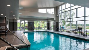 A swimming pool with clear blue water, surrounded by large windows offering views of greenery and a parking area. - Residence Inn by Marriott Lancaster (Lancaster)