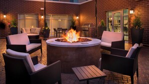 An outdoor patio with a fire pit, wicker furniture, and a brick building in the background. - Residence Inn by Marriott Lancaster (Lancaster)