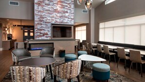 A modern lounge area with a brick accent wall, a flat-screen TV, comfortable seating, and a fireplace. - Residence Inn by Marriott Lancaster (Lancaster)