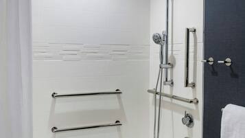 A modern bathroom with a white bathtub, a shower with a handheld showerhead, and a towel rack.