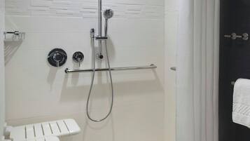 A walk-in shower with a glass door, a handheld showerhead, a handheld shower attachment, and a white towel rack.